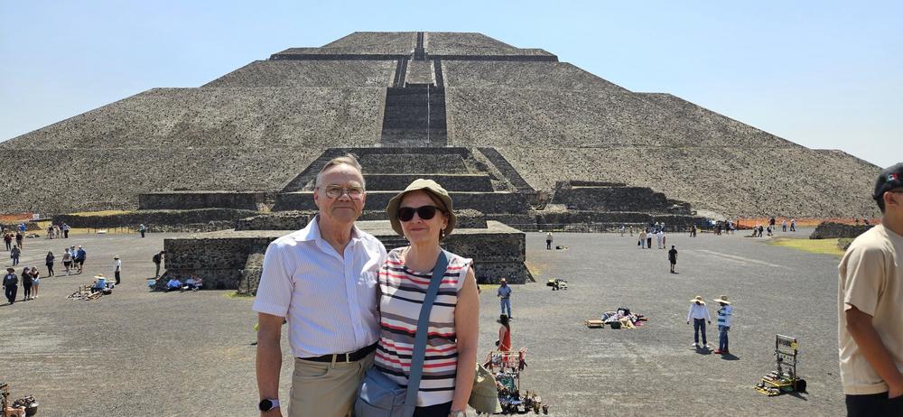 Pariskunta poseeraa vantavan kivipyramidin edessä. 