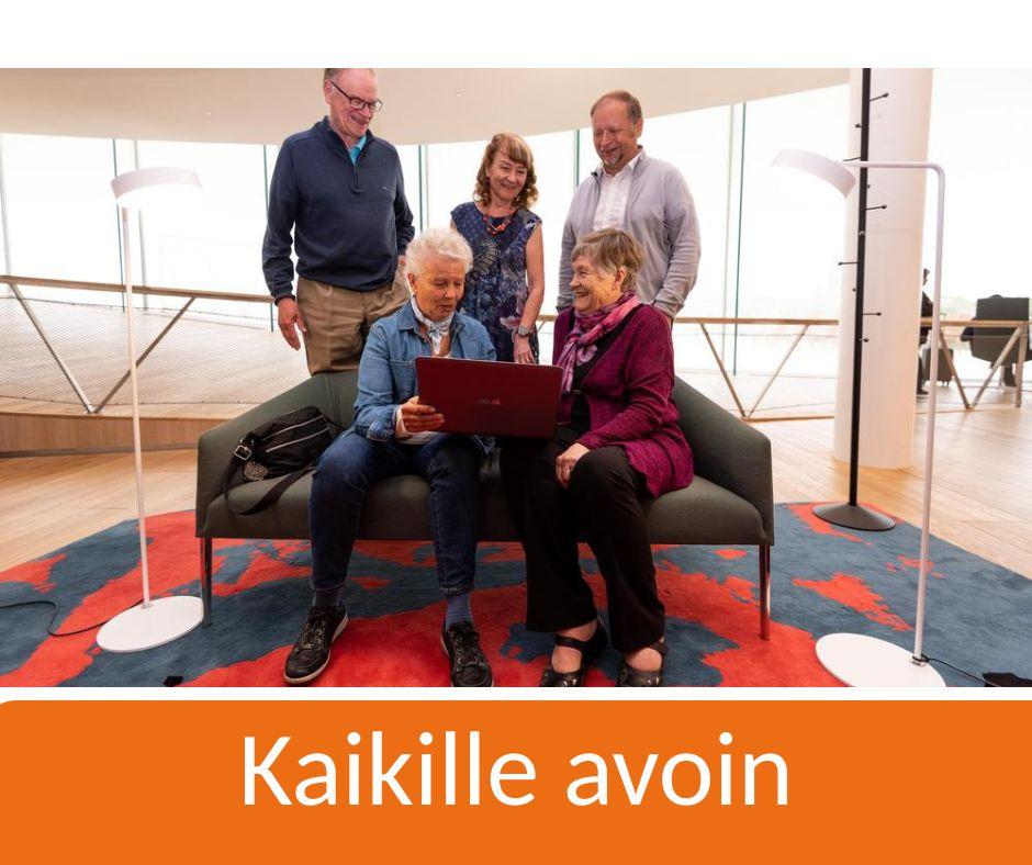 Kuvassa on joukko senioreita keskustelemassa sohvan ympärillä ja katsomassa tietokonetta.