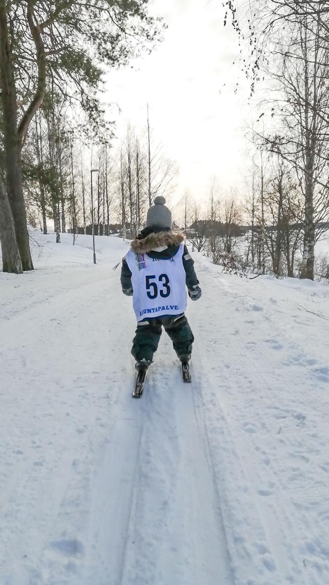Lapsi hiihtämässä latua numerolappu selässään.