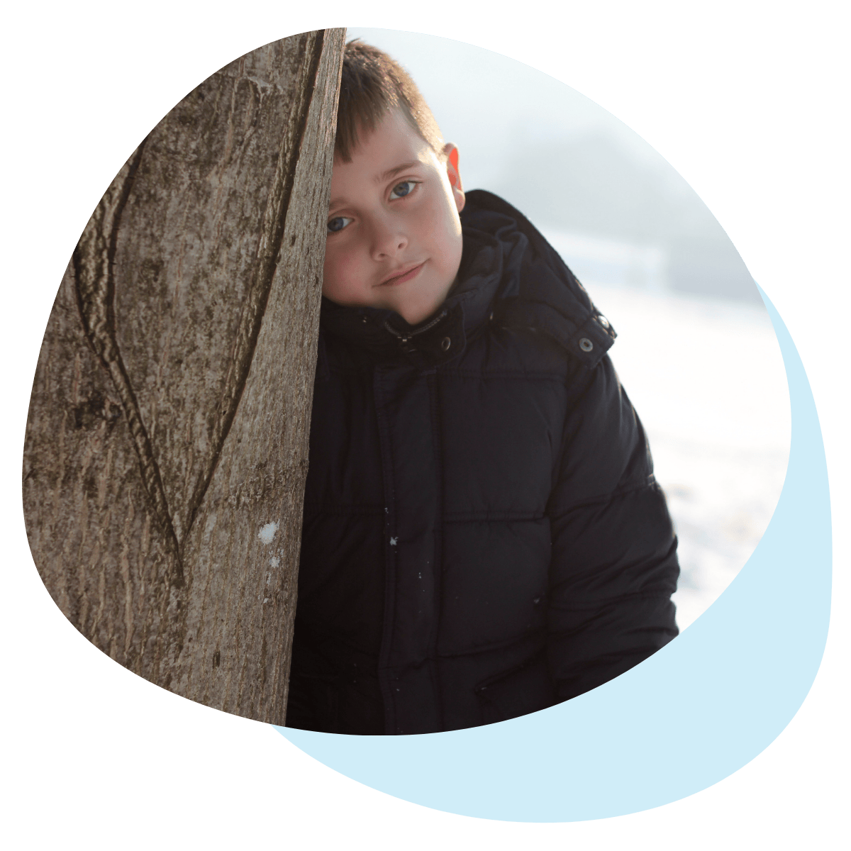 Kiusattu alakouluikäinen poika nojaa yksin puuta vasten mustassa takissa