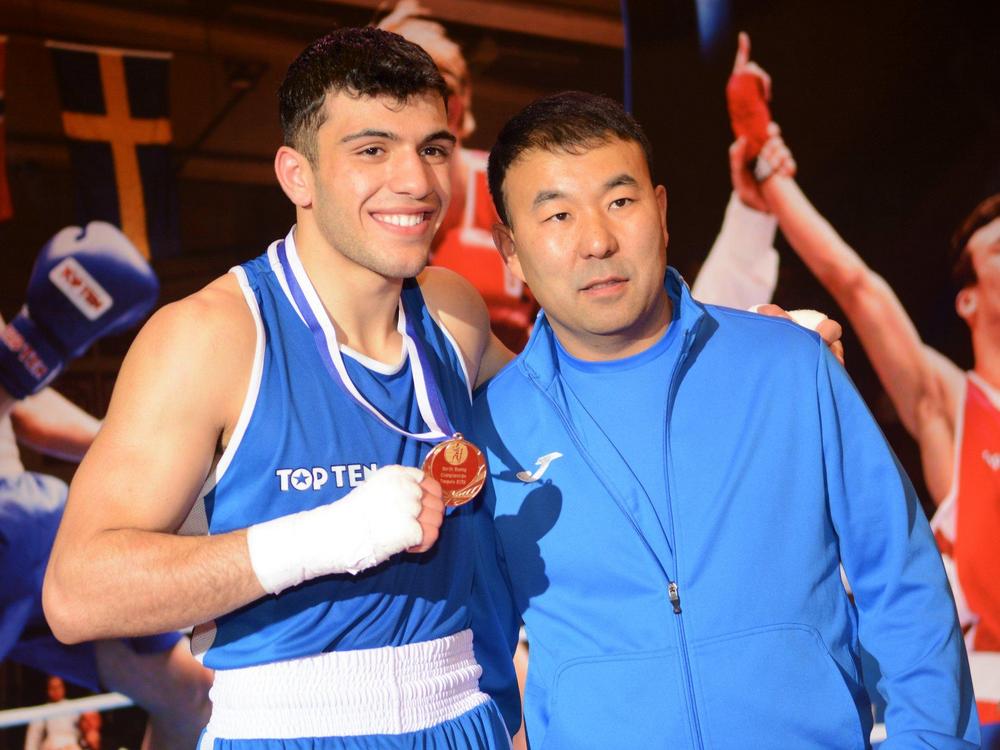 Nyrkkeilijä ja valmentaja palkintokorokkeella.