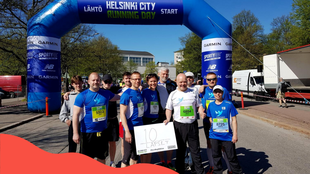 Noin yksitoista ihmistä Helsinki City Running Dayn lähtöalueella poseeraa kameralle hymyillen