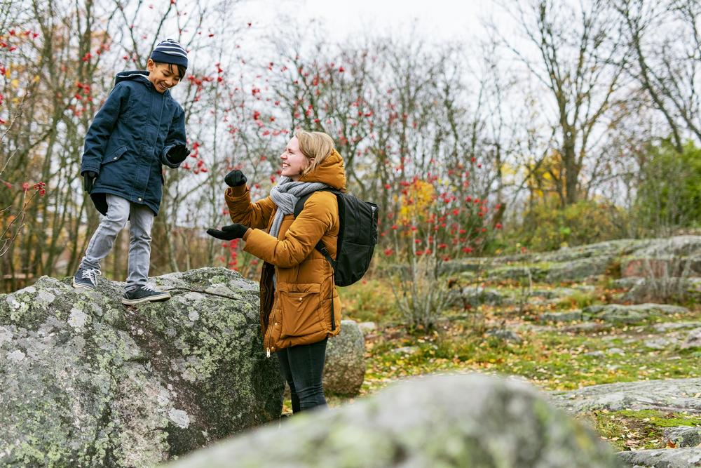 Nainen ja poika leikkivät ulkona syksyisessä säässä.