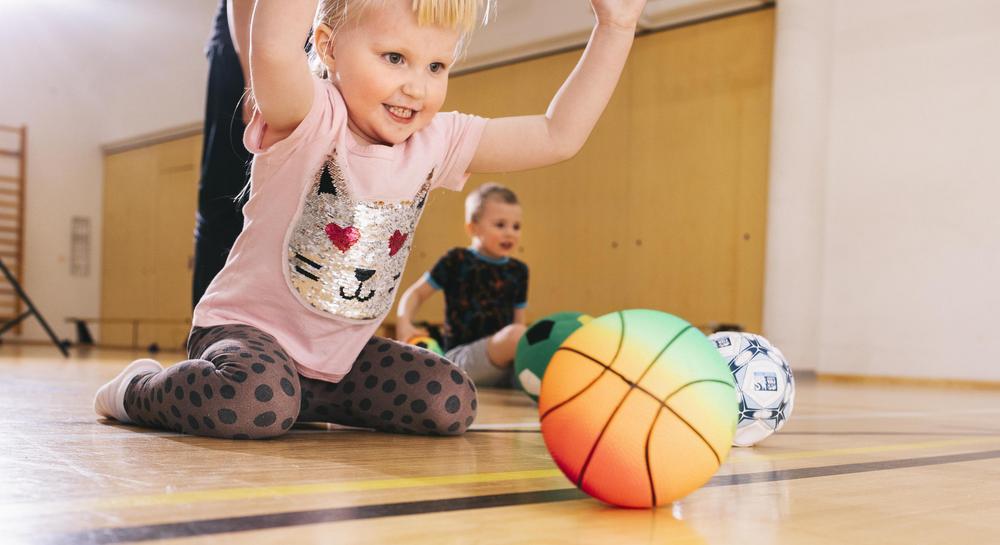 Lapset leikkivät palloilla liikuntasalissa.