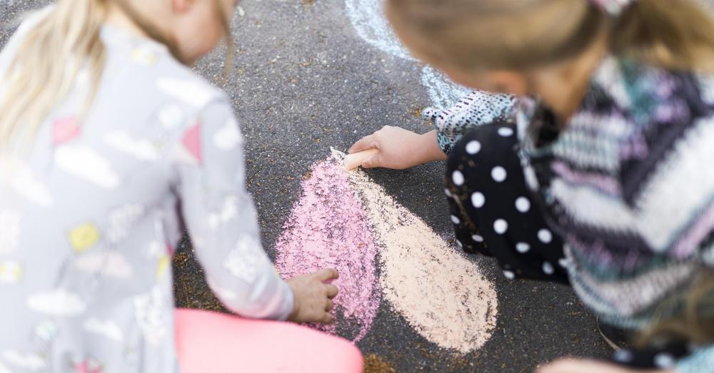 Kuvassa lapset piirtävät katuliiduilla sydämen