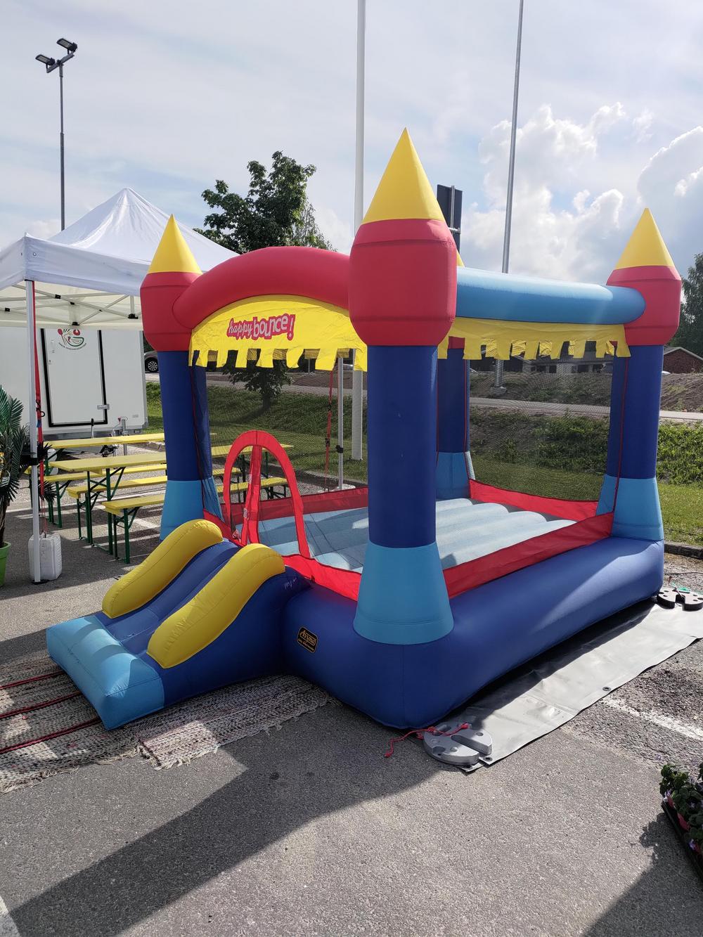 Värikäs pomppulinna auringonpaisteessa asfalttipihalla.