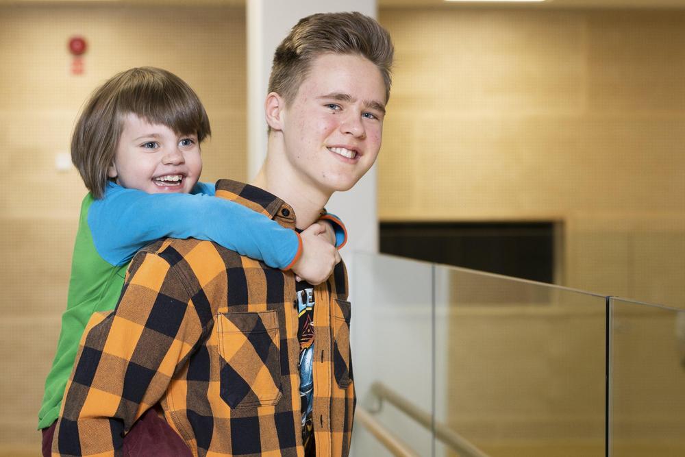 Kerhonohjaaja kantaa kerholaista reppuselässä