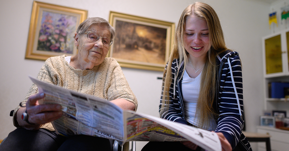 Nuori ja seniori-ikäinen rouva lukevat lehteä.