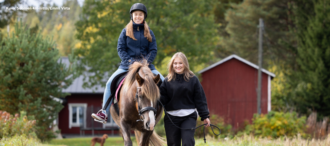 Kaksi nuorta ulkona kesällä, joista toinen ratsastaa ruskean hevosen selässä. Kuva : Suomen 4h-liitto - Emmi Virta