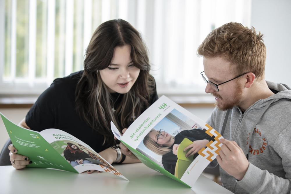 4H-yhdistyksen työntekijä pitää 4H Cafe -kahvilaa yläkoulun aulassa. Työntekijän ympärillä nuoria.