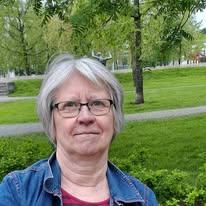 Riitta istuu puistossa hymyillen