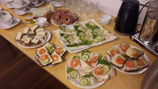 Pöydällä on lautasia, joilla on erilaisia voileipiä sekä porkkanakakkua ja munkkeja.