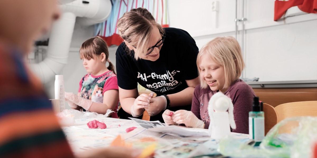Iloisia ja hymyileviä lapsia Oulun 4H:n iltapäivätoiminnassa luotettavan aikuisen seurassa.