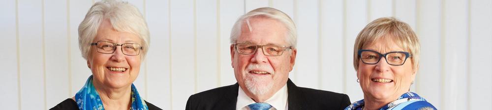 Kolme senioria juhlavaatteissa poseeraamassa