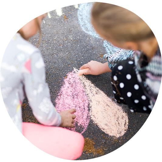 Lapset piirtävät katuliiduilla asfalttiin sydäntä.