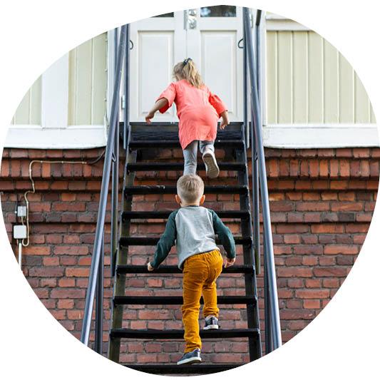 Kaksi lasta kiipeää portaita ylöspäin.