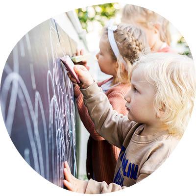 Lapset piirtävät liitutaululle.