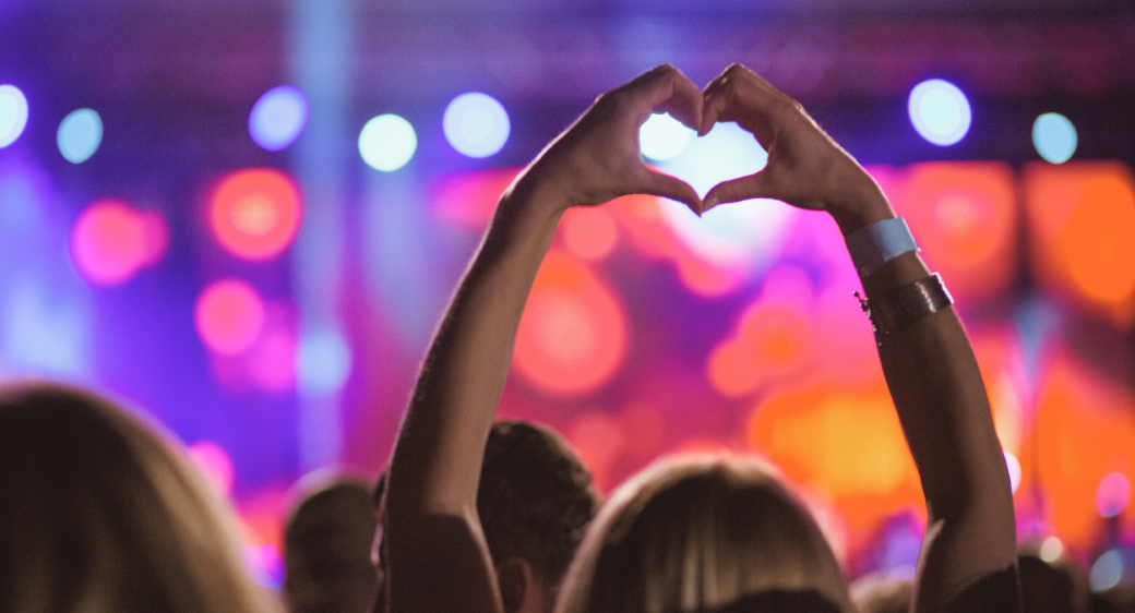 Audience at a cultural event, a woman making heart with her hands.
