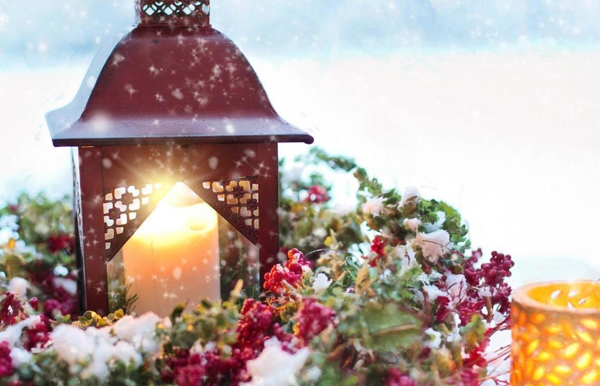 Kynttilä palaa lyhdyssä, lyhdyn ympärillä jouluinen kranssi.
Kuva Pixabay.