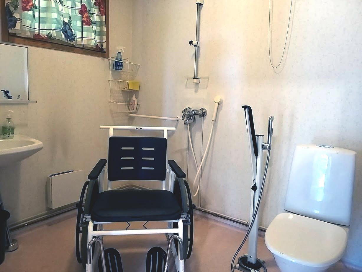Invawc-tilassa näkyy lavuaari, suihku, pyörätuoli ja vessanpönttö.