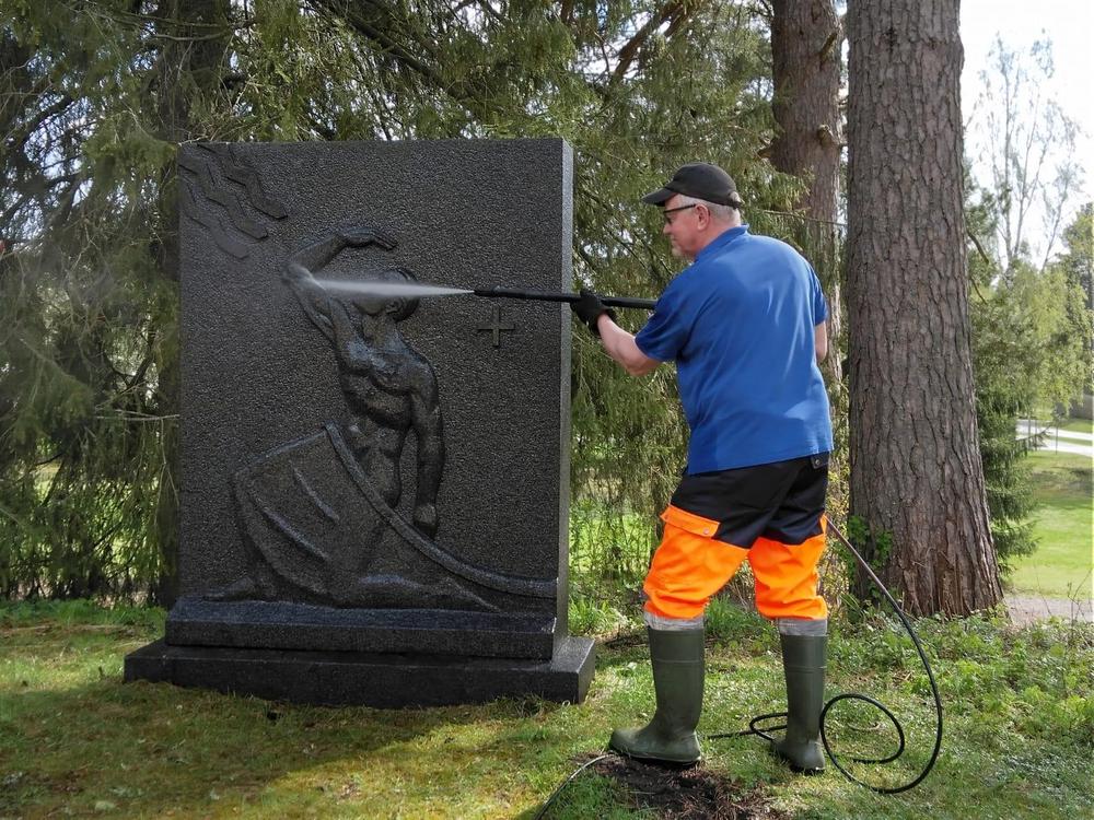 Muhoksen rotaryklubin klubimestari Juhani Paakki puhdistaa Muhoksen kirkon pihalla olevaa sankarihautausmaan muistomerkkiä.