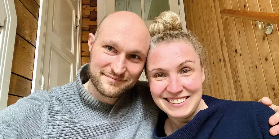 Hannu Liitsola pitää Hilkka Liitsolaa kainalossaan samalla, kun he molemmat hymyilevät iloisesti kameralle.