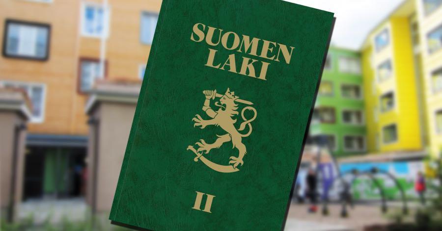 Vihreäkantinen Suomen lakikirja taustallaan värikkäitä kerrostaloja.