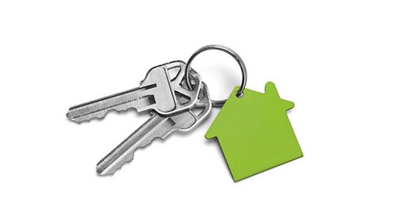 Kaksi avainta, joissa on ääriviivoiltaan talon muotoinen vihreä avaimenperä. 