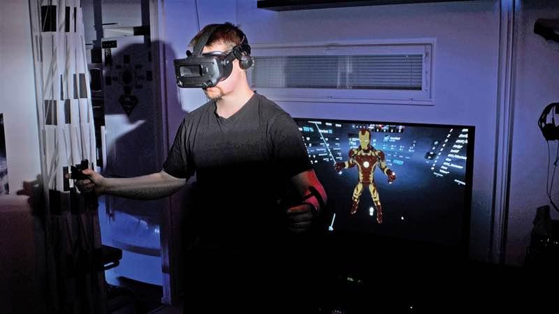Mies olohuoneessaan pelaamassa VR-lasit päässään tietokonepeliä.