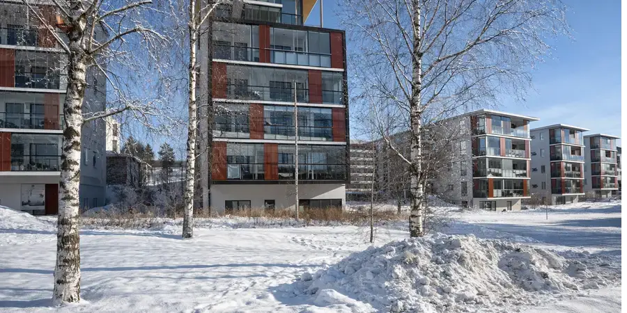 Talvinen kaupunkimaisema, jossa etualalla näkyy viisi vaaleansävyistä kerrostaloa.
