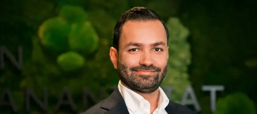 Kasvokuva tummaan puvuntakkiin ja valkoiseen kauluspaitaan pukeutuneesta hymyilevästä miehestä.