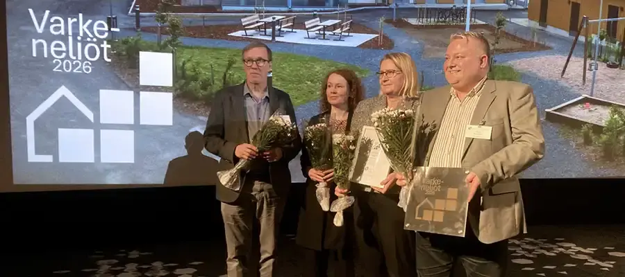 Kaksi naista ja kaksi miestä esiintymislavalla kukkakimput käsissään.