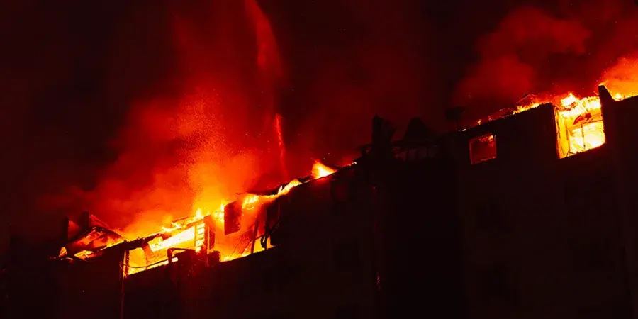 Kerrostalon katto liekeissä yön pimeydessä.