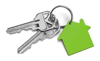 Mot en vit bakgrund finns en nyckelring, varifrån hänger två nycklar och en husformad nyckelring.