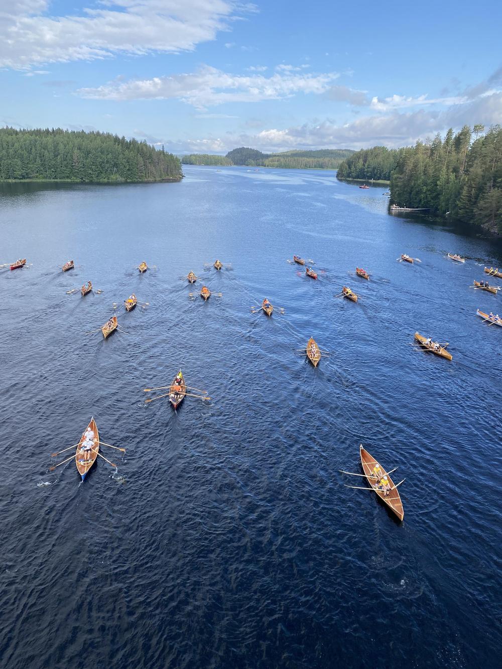 Useita veneitä soutajineen järvellä.