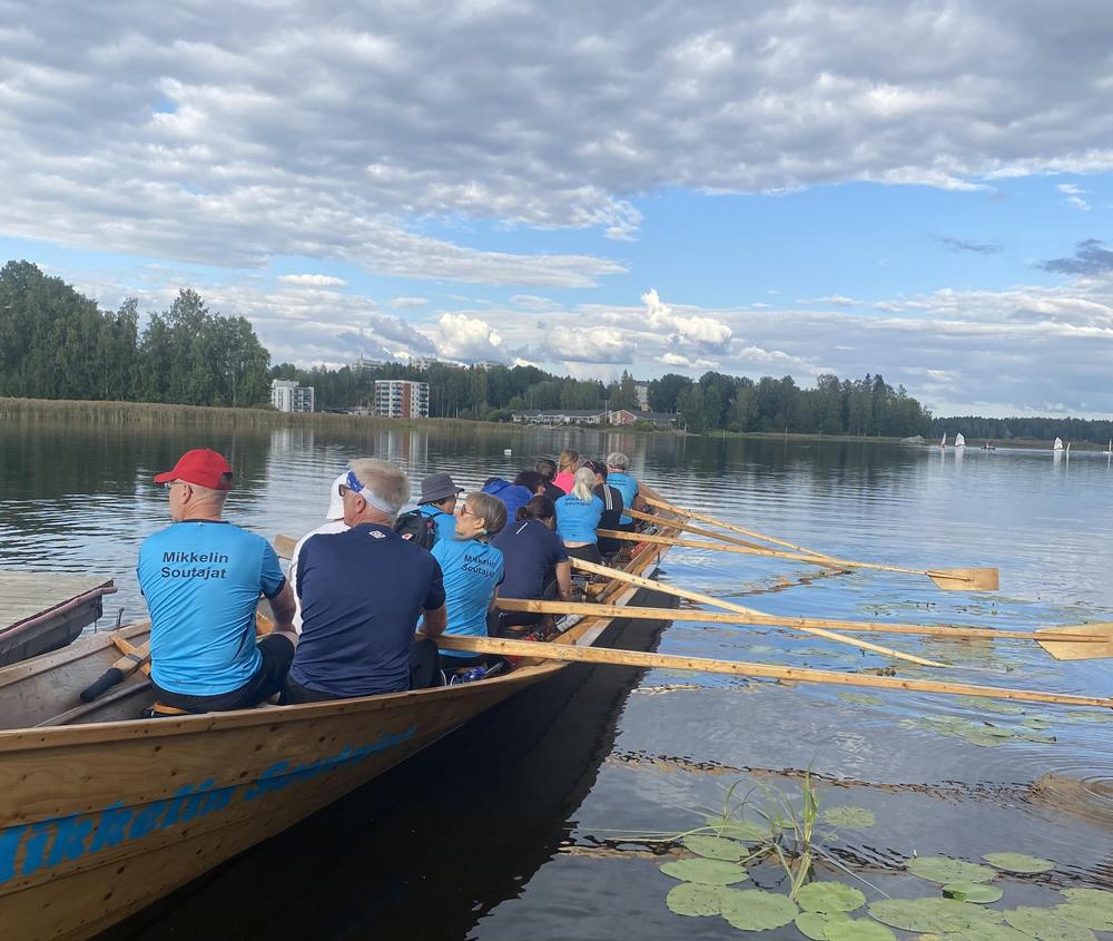 Ihmisiä soutamassa yhdessä isossa puuveneessä. 