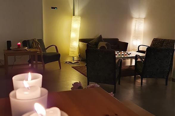 Hämärä huone, jossa tuoleja ja pöytä sekä valoja ja kynttilöitä.