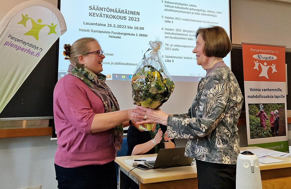 Pienperheyhdistyksen puheenjohtaja Taija Liuhto ojentaa kukat Kunniajäseneksi valitulle Tytti Salmiselle.