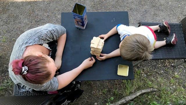 Äiti ja lapsi kasaavat palikoita pöydän ääressä Pienperheyhdistyksen leirillä.