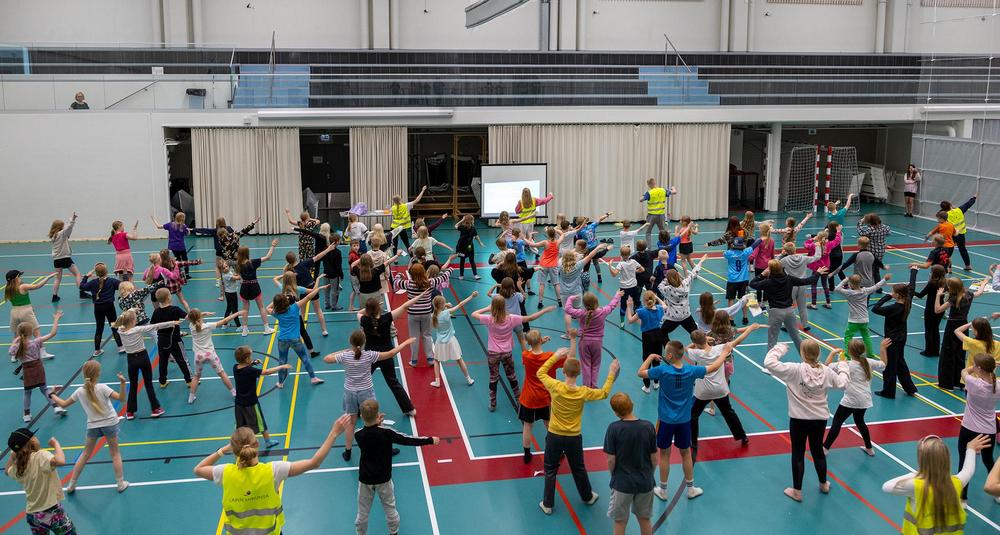 Kuvassa lapset jumppaavat liikuntahallissa.