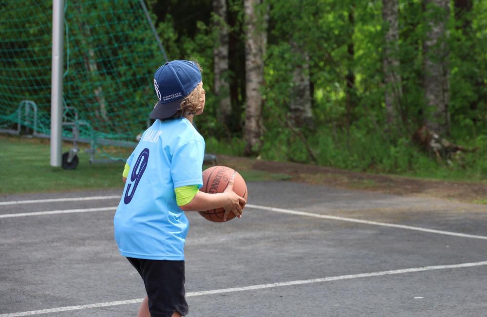 Poika heittää koripalloa.