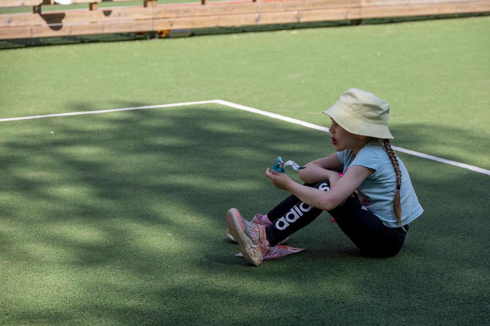 Lapsi istuu syömässä urheilukentällä.