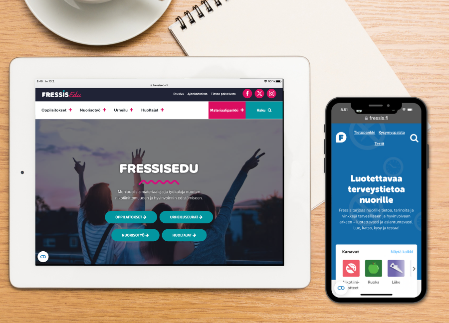 Kahvikuppi, paperilehtiö, tabletti ja puhelin pöydällä. Tabletin näytöllä on opettajille suunnattu FressisEdu.fi-sivusto ja iPhonen näytöllä oppilaille suunnattu Fressis.fi-sivusto.