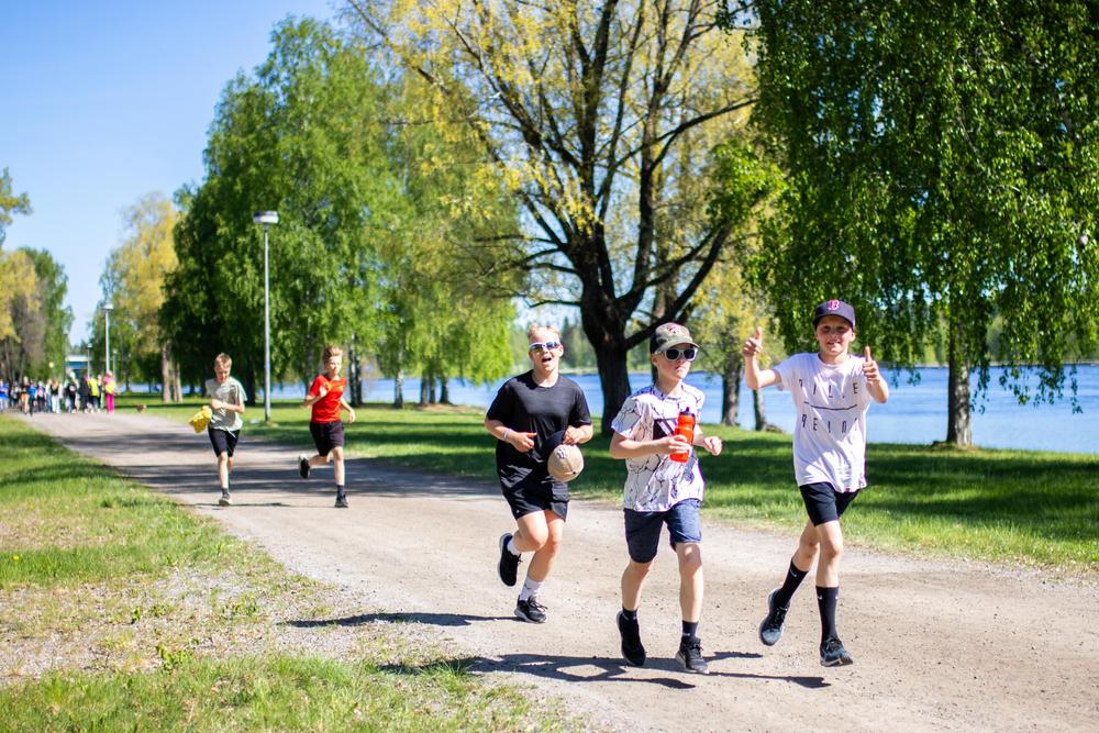 Kolme poikaa juoksemassa Imatralla Vuoksen varrella Koulumaraton reitillä, yksi näyttää peukkuja ylöspäin