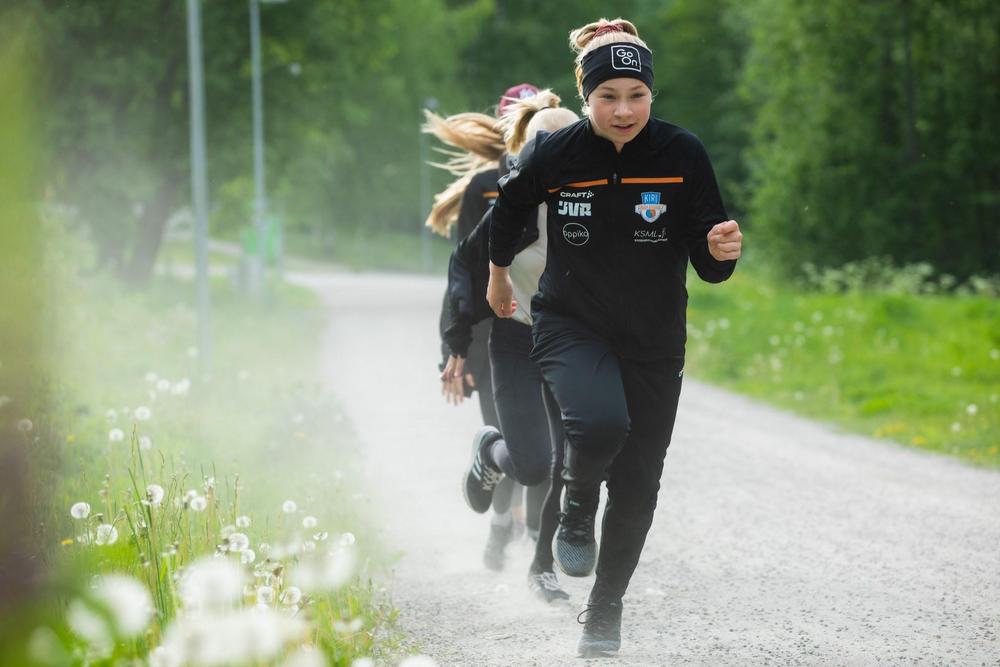 Tyttöjä juoksemassa jonossa hiekkatiellä