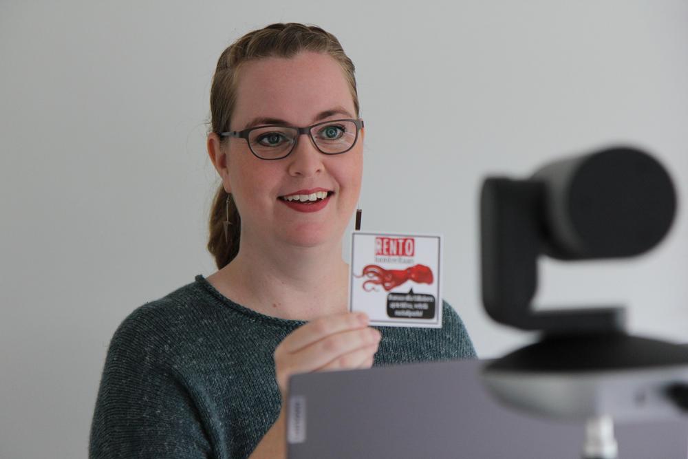 Hymyilevä Suomen Kivun järjestökoordinaattori Heidi Krogell näyttää kameralla korttia, jossa lukee rento.