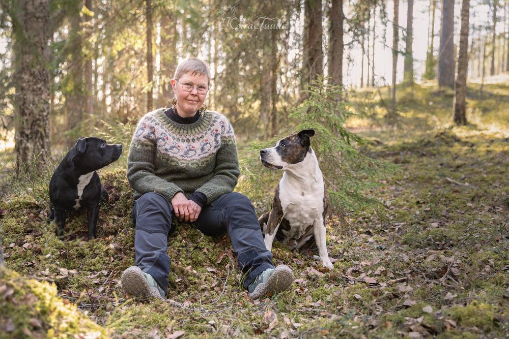 Yhdistyksen tiedottaja Liisa ja hänen koiransa istumassa metsän keskellä. 