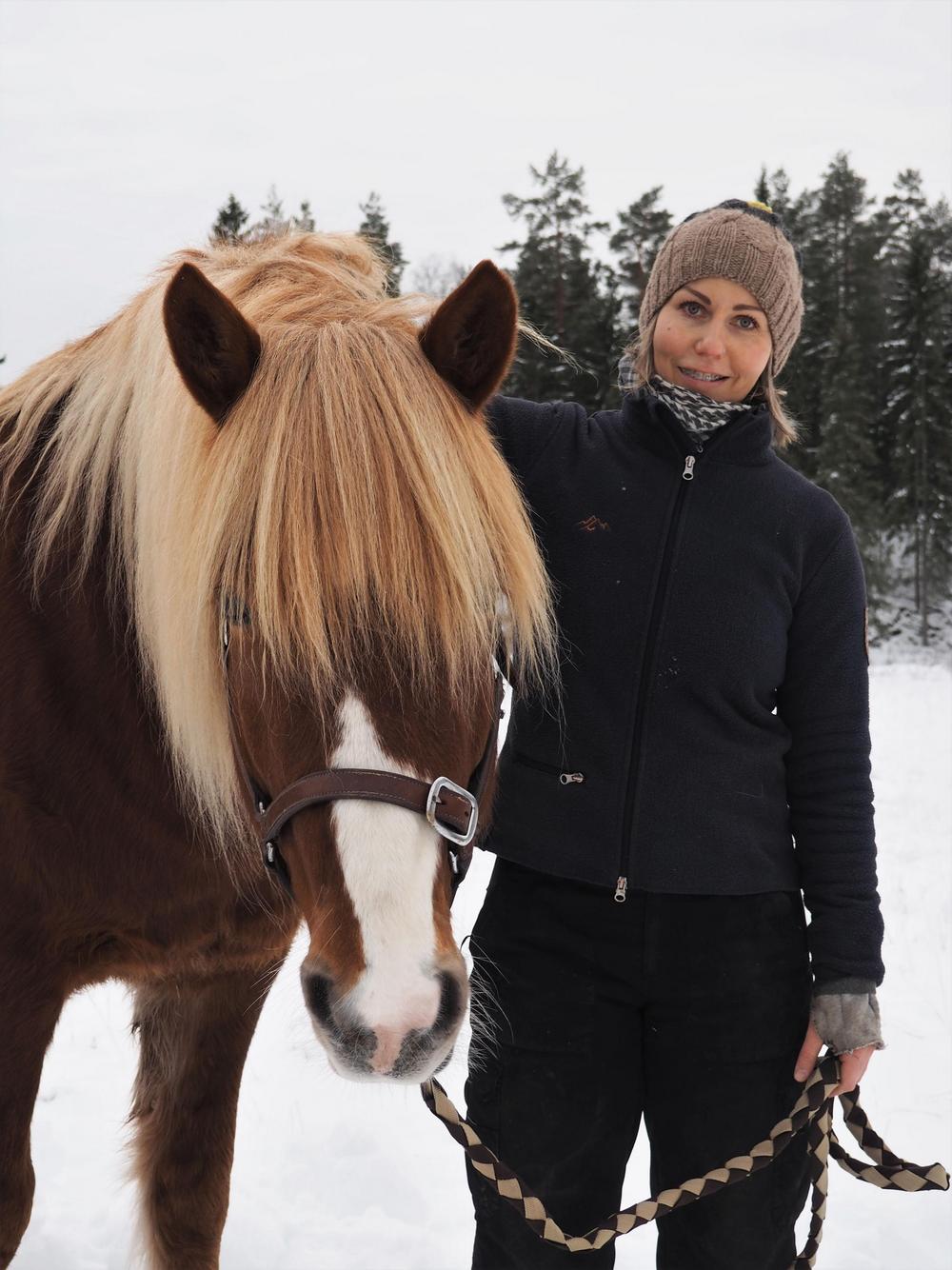 Hallituksen varajäsen Anu talvisessa maisemassa hevosen kanssa viereikkäin.