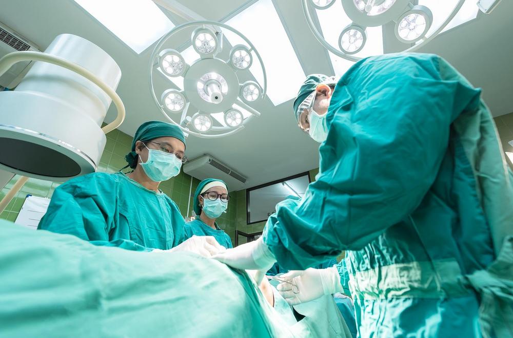 Kuvituskuvassa leikkaus käynnissä sairaalassa, kuva alakulmasta leikkauspöydästä katsoen.