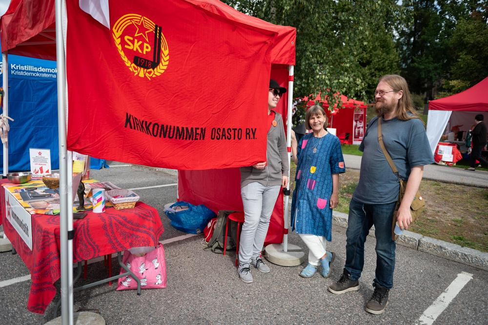 Tovereita juttelemassa iloisesti SKP:n teltalla SKP:n Kirkkonummen osaston lipun vieressä.